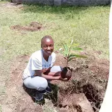 An image of Bikoro with a loquat tree seedling in hand ready for planting